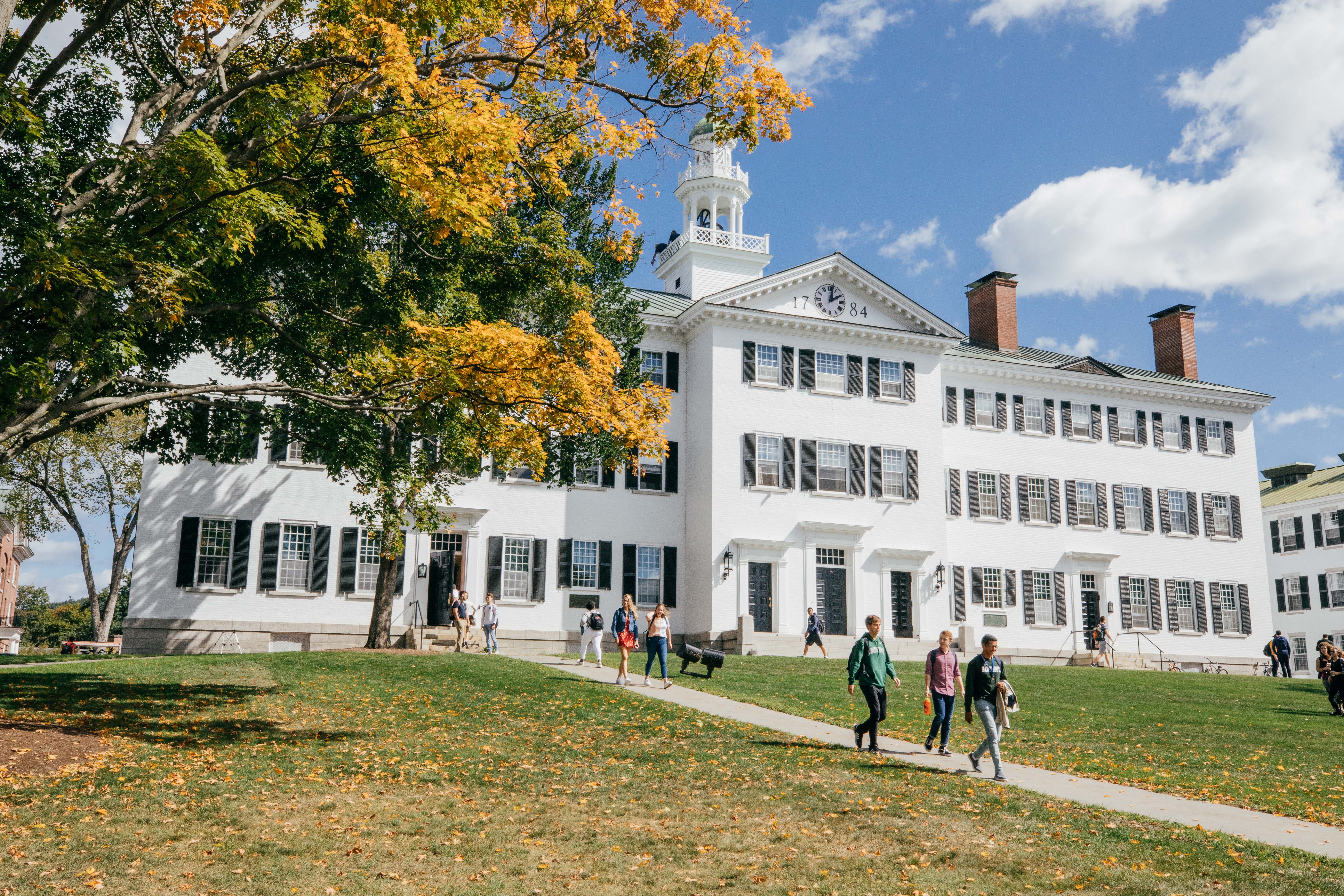 The front of Dartmouth Hall in the fall with students entering and exiting the building